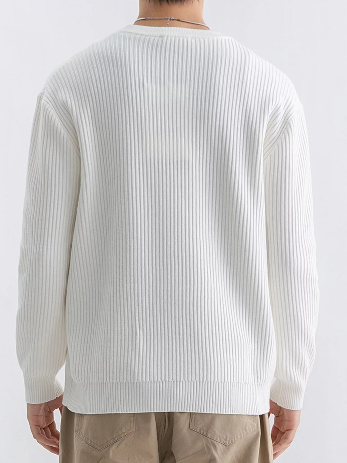 NEWYORKLISTED ATLAS MEN'S COLLECTION: A person shown from the back wearing a ribbed knit long-sleeve sweater in off-white, paired with beige pants, against a plain light background.