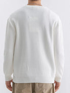 NEWYORKLISTED ATLAS MEN'S COLLECTION: A person shown from the back wearing a ribbed knit long-sleeve sweater in off-white, paired with beige pants, against a plain light background.
