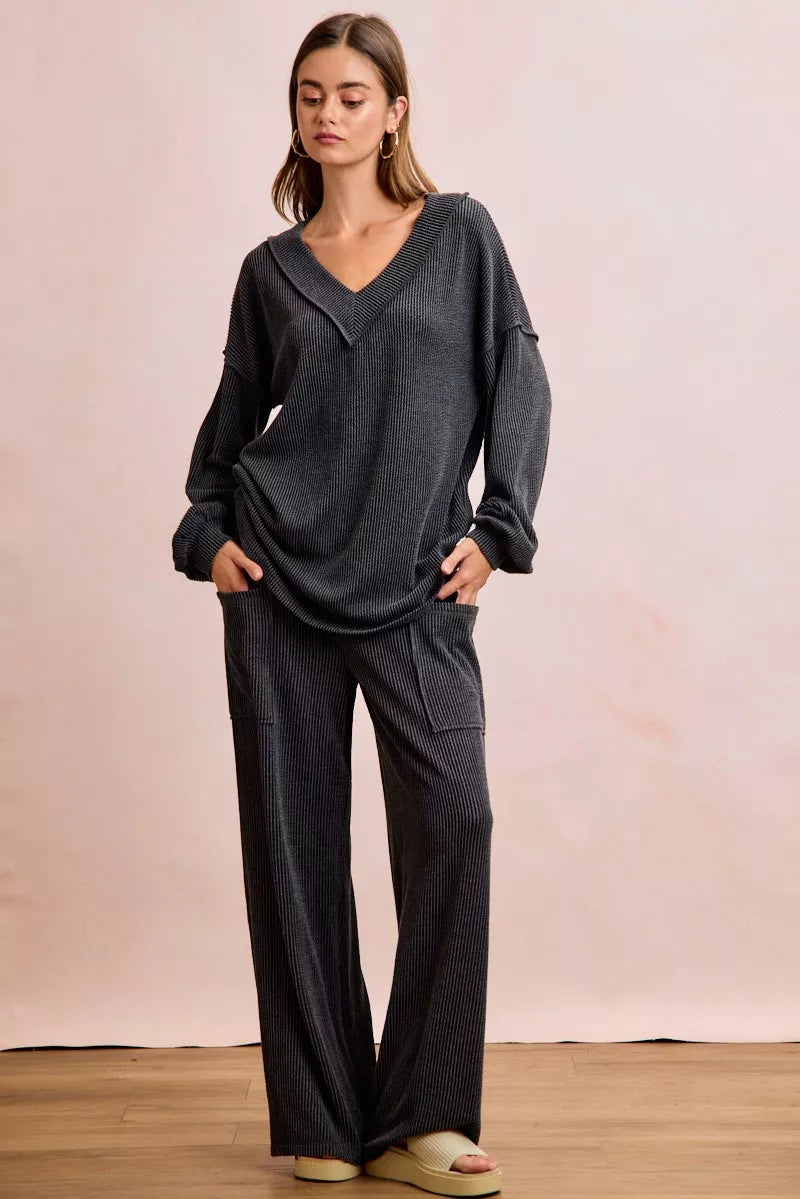 NEWYORKLISTED Comfort Collection: Woman wearing a dark gray outfit with wide-leg pants against a plain background