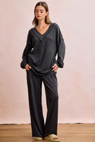 NEWYORKLISTED Comfort Collection: Woman wearing a dark gray outfit with wide-leg pants against a plain background