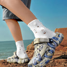 NEWYORKLISTED ATLAS MEN'S COLLECTION: Person wearing patterned sandals and white socks by the ocean