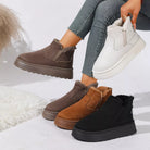NEWYORKLISTED SHOE COLLECTION: Four slip-on platform ankle boots in brown, tan, black, and white are displayed on a white studio floor, with a person's legs and hand holding one of the white boots.
