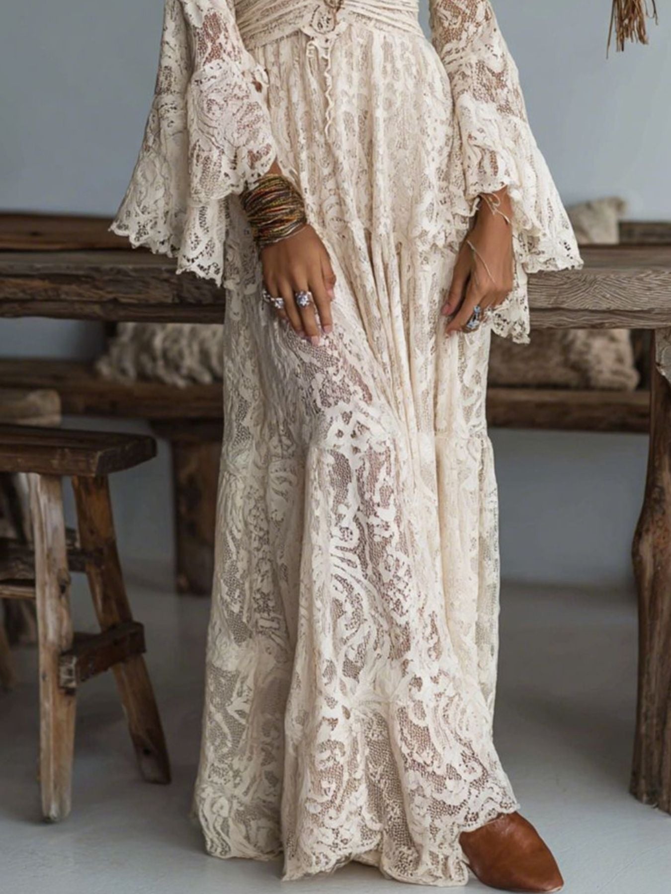 NEWYORKLISTED STYLE COLLECTION: Person wearing a lace dress with bell sleeves in a rustic setting.