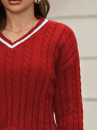 NEWYORKLSITED STYLE COLLECTION: Close-up of a person wearing a red cable knit sweater with a blurred background