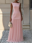 NEWYORKLISTED STYLE COLLECTION: Woman wearing a pink dress standing on a stone pavement with a textured wall background