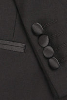 Close-up of a dark gray suit jacket with buttons and a lapel.