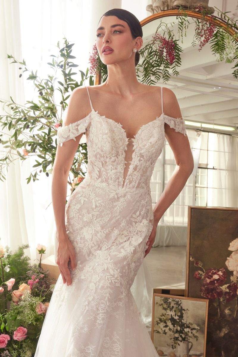 NEWYORKLISTED ELEGANT BRIDE COLLECTION: Woman wearing a white lace wedding dress in a decorated room with flowers and mirrors.