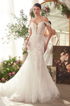 NEWYORKLISTED ELEGANT BRIDE COLLECTION: Woman in a white wedding dress standing in a decorated room with flowers and mirrors.